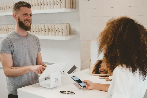 Kundin bezahlt kontaktlos mit dem Smartphone an der Kasse